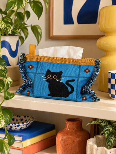 blue cat knitted tissue pouch on a wood shelf beside books and a plant