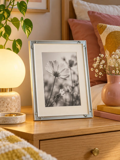 silver aluminum frame with abstract print leaning on a floating shelf