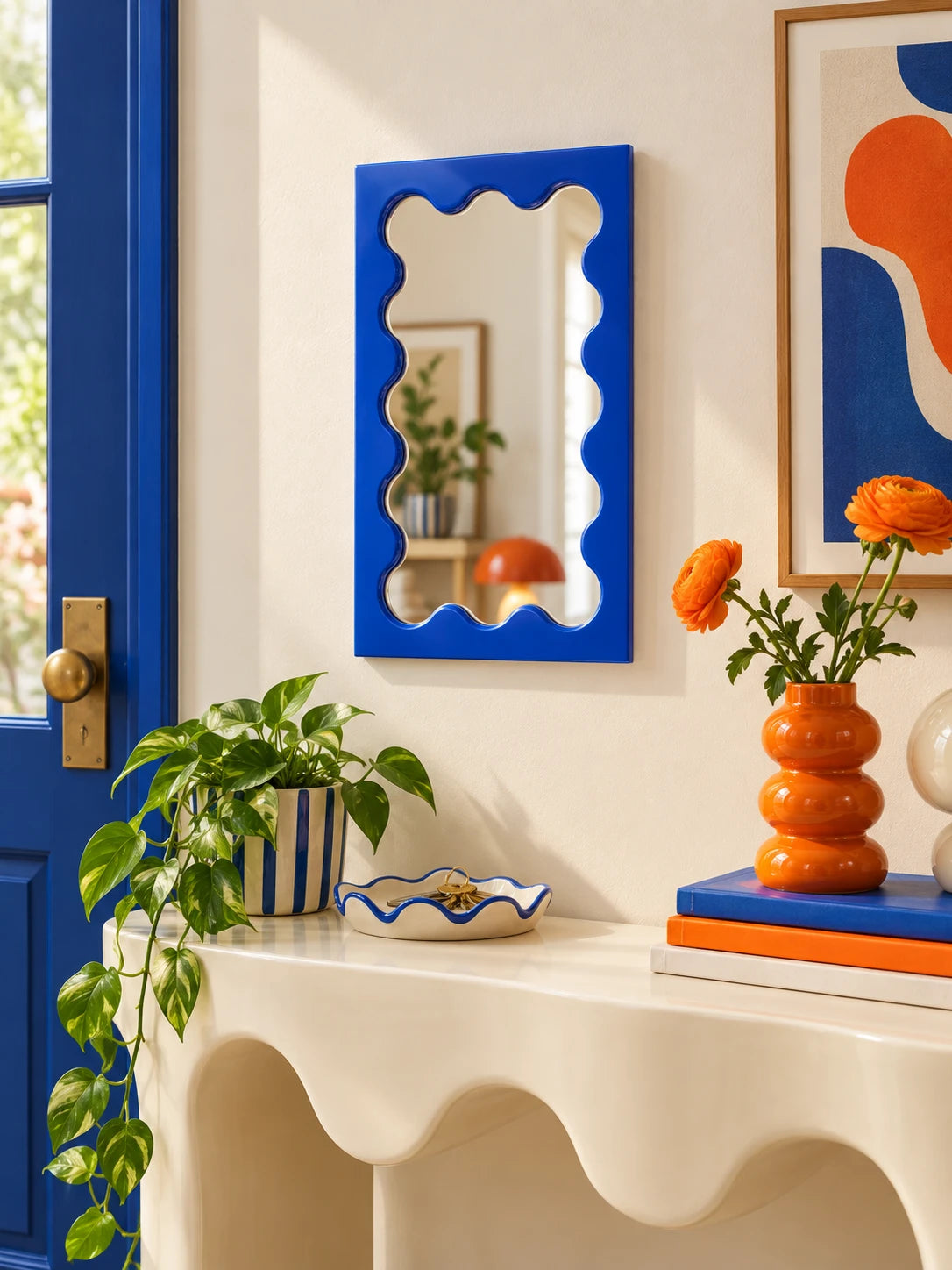 Cobalt blue wavy vanity mirror above a styled console with decor objects