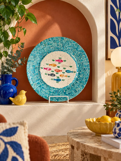 Seashell mosaic fish tray in a terracotta arched niche with a yellow bird figure