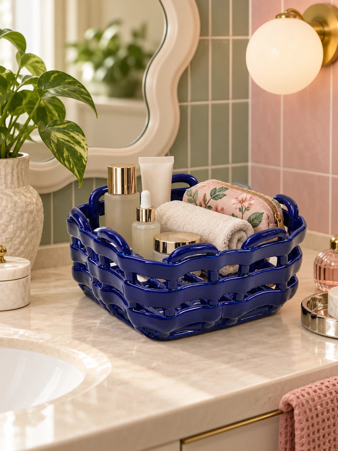 
Cobalt woven ceramic basket with rolled towels and skincare on a bathroom counter
