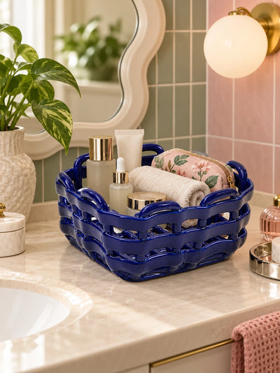 Cobalt woven ceramic basket with rolled towels and skincare on a bathroom counter