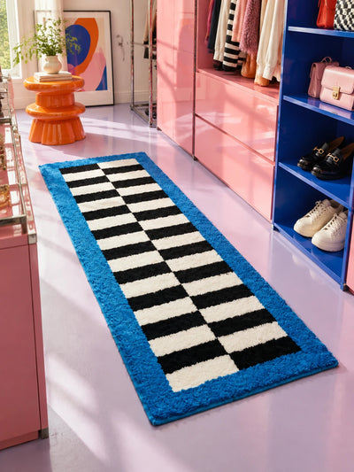 Checkerboard runner rug in a pink and cobalt walk-in closet with shoes on blue shelves