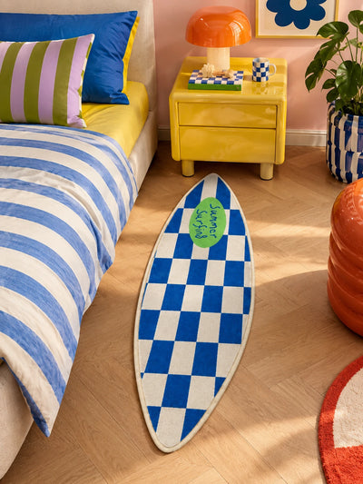 Surfboard bedside rug on herringbone floor next to a yellow nightstand and orange mushroom lamp