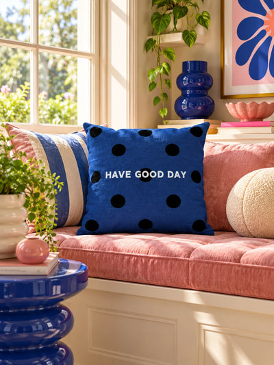 navy polka dot slogan pillow on a pink window seat with an open book