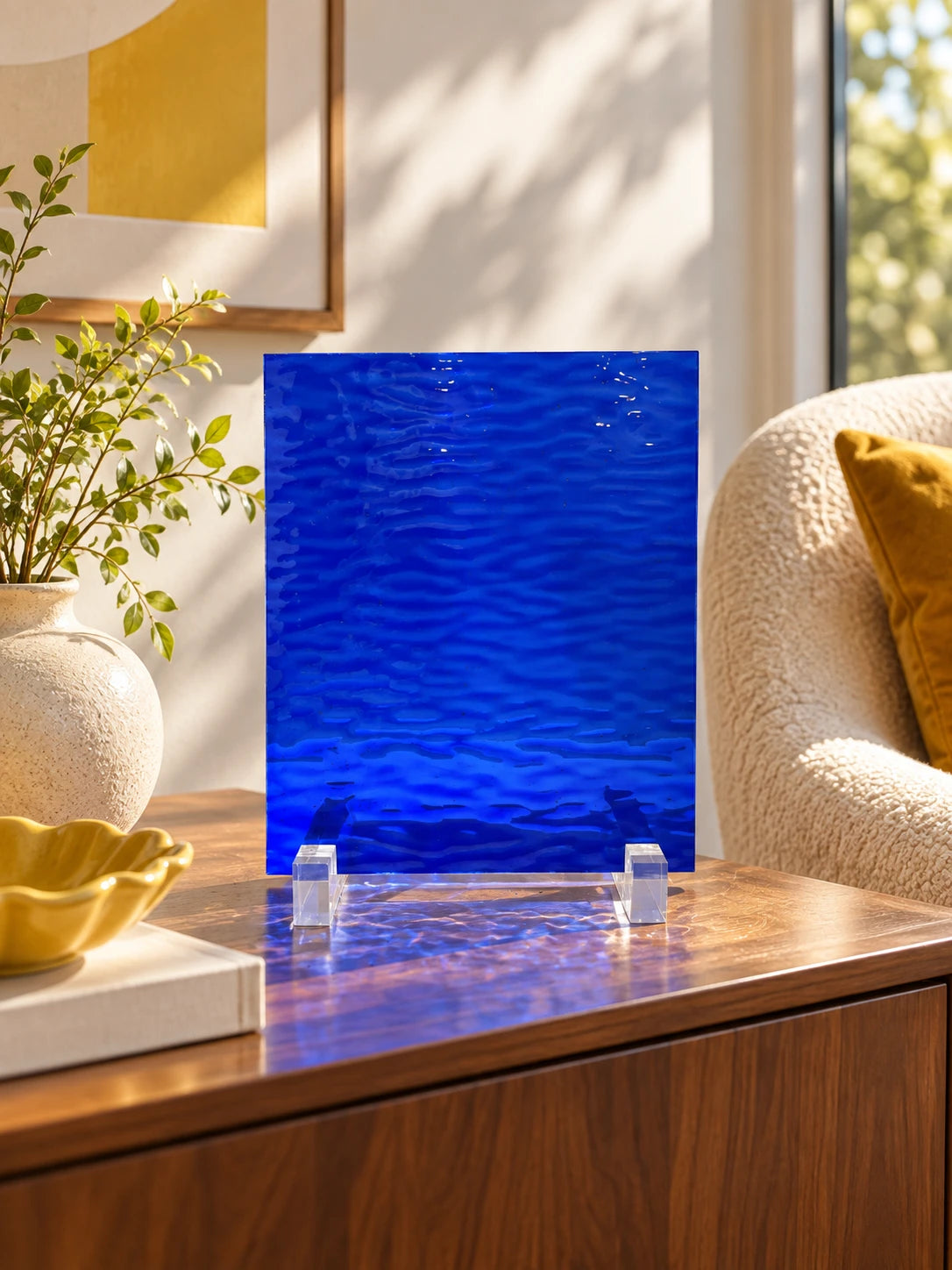 cobalt rippled glass sheet on a wood cabinet beside a boucle chair