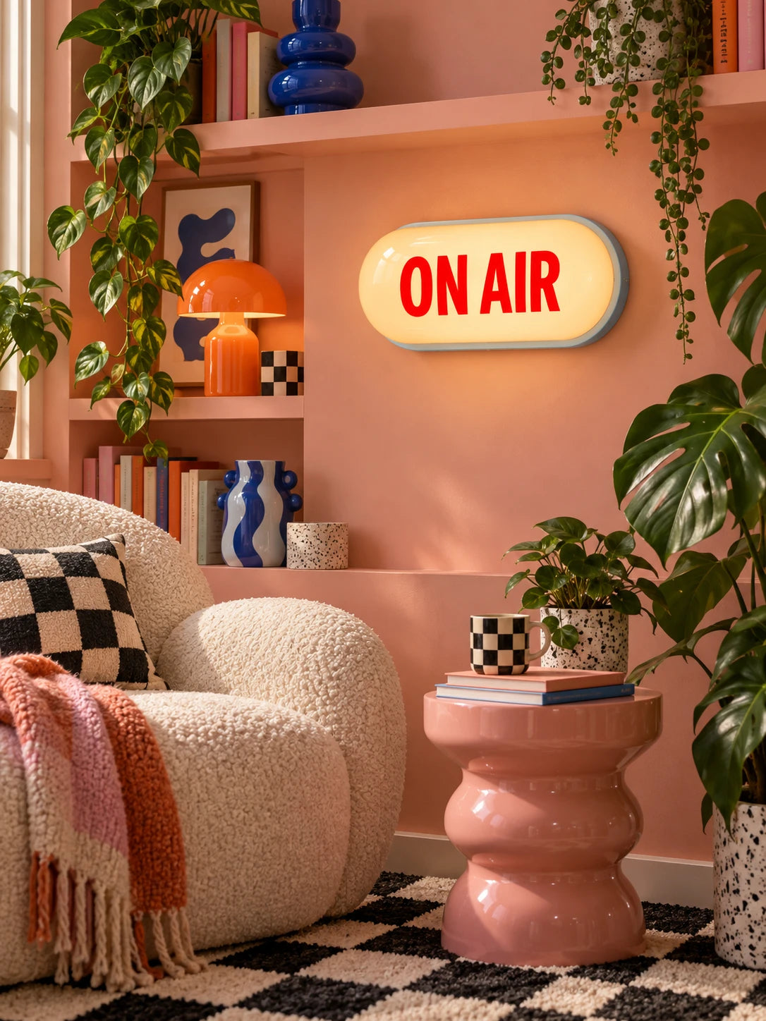 
Warm-lit ON AIR sign in a peach shelving nook beside an orange mushroom lamp and pink stool