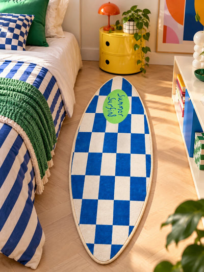 Checkerboard surfboard rug beside a bed with blue striped bedding and yellow round nightstand