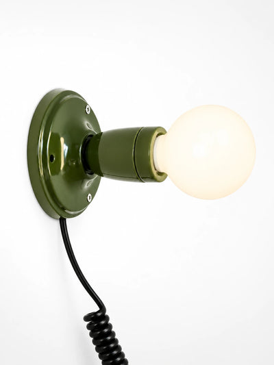 olive green ceramic wall light with an opal globe bulb and coiled black cord, studio shot on white