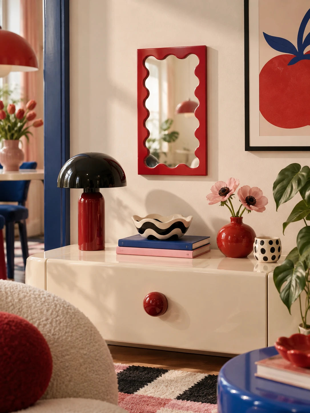 Red wavy-frame vanity mirror over a styled console with colorful accents