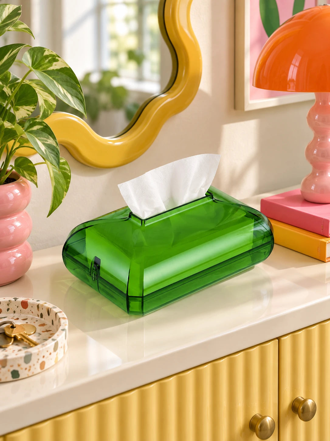 Green acrylic tissue box on a white console under a yellow wavy mirror