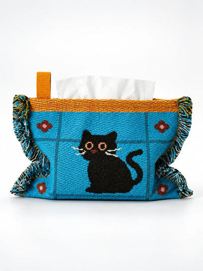 blue knitted tissue holder with black cat design, mustard trim and tassels, studio view