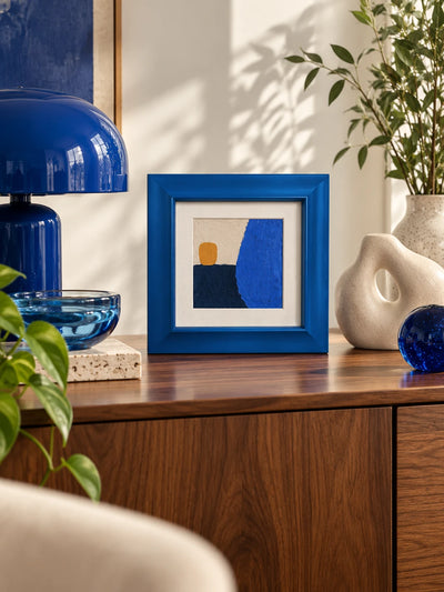 cobalt wood frame with blue abstract standing on a walnut sideboard