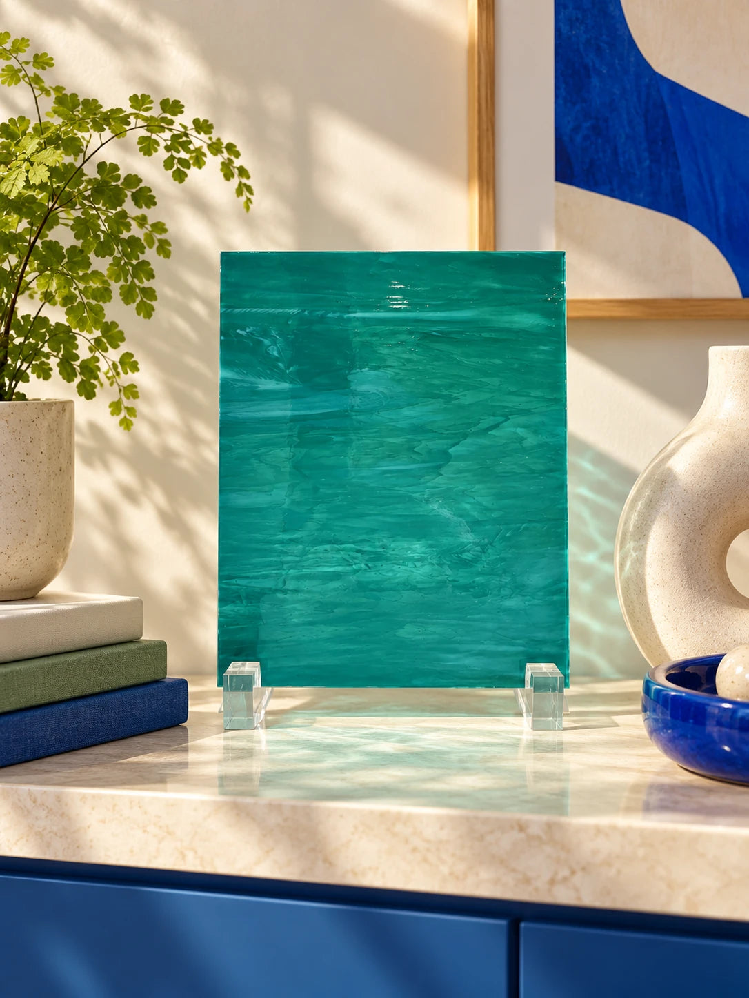 teal rippled glass sheet on a shelf with books and a donut vase