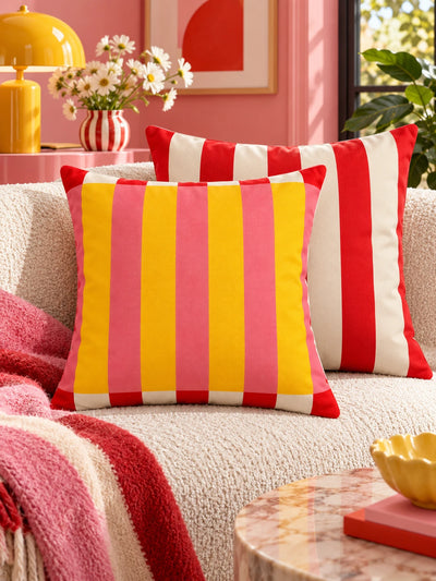 Yellow and pink stripe pillow with red striped pillow in a pink room with daisies