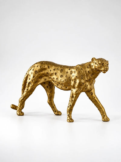 gold-finish resin cheetah statue with hammered spots in a walking pose, studio shot on white