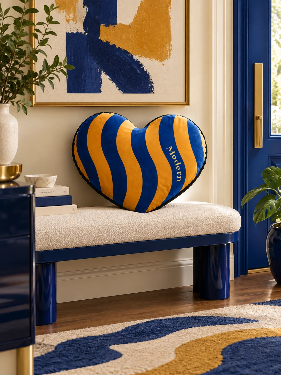 Blue and marigold heart pillow on an entry bench beside a cobalt blue door