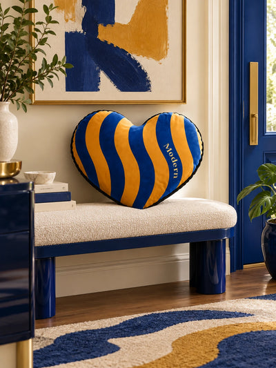 Blue and marigold heart pillow on an entry bench beside a cobalt blue door