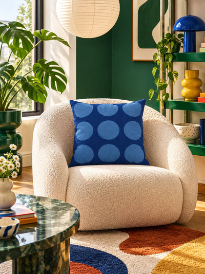 blue dot-grid pillow on a boucle chair against a red and white striped wall