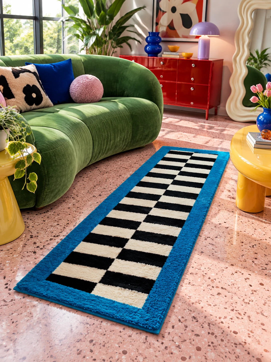 
Black and cream checkerboard runner on pink terrazzo by a green velvet sofa and a red dresser