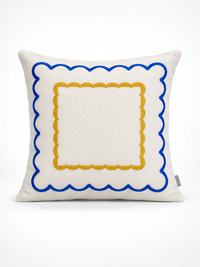 Cream throw pillow with a cobalt scalloped border and an inner mustard scalloped square, studio shot