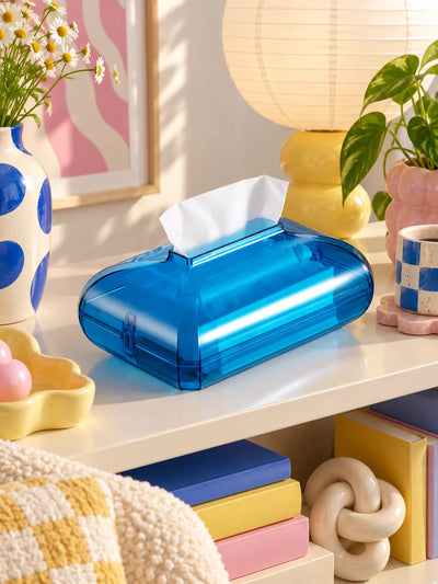 Blue acrylic tissue box on a shelf beside a polka-dot vase and paper lantern lamp