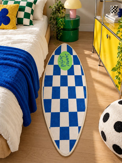 Surfboard runner rug alongside a bed with royal blue blanket and yellow metal cabinet