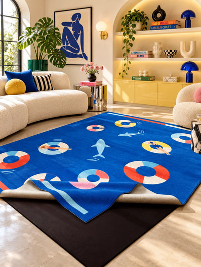 Cobalt pool party rug in a living room with a curved cream sofa, a blue figure print and lit yellow shelves