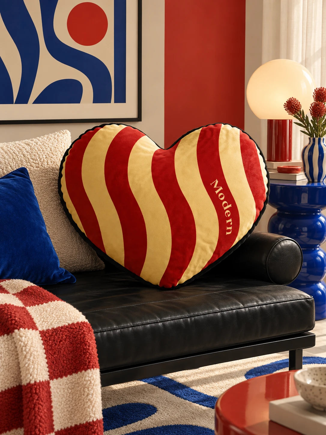 Red and cream heart pillow on a black leather daybed with checkered throw