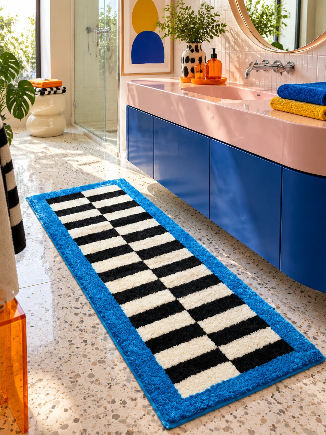 
Blue border runner rug on a terrazzo bathroom floor along a cobalt vanity with a pink counter