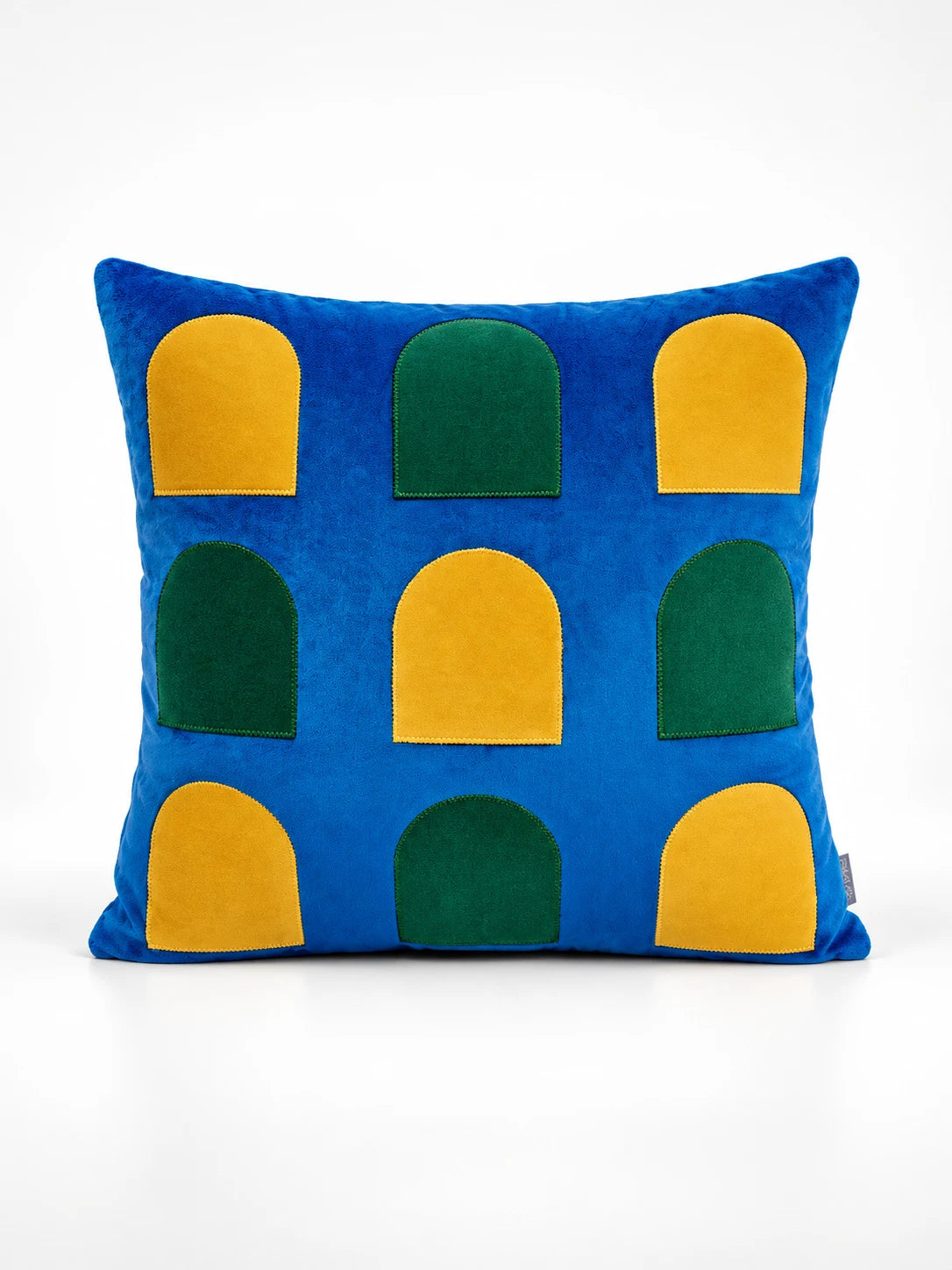 
Cobalt velvet throw pillow with rows of yellow and green arched window shapes, studio shot