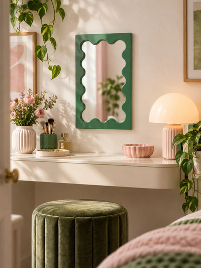 Avocado green wavy mirror above a dresser styled with books and a vase