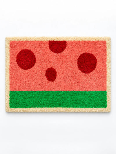 watermelon flocked bath mat in coral pink with dark red dots, green stripe and cream border, studio view