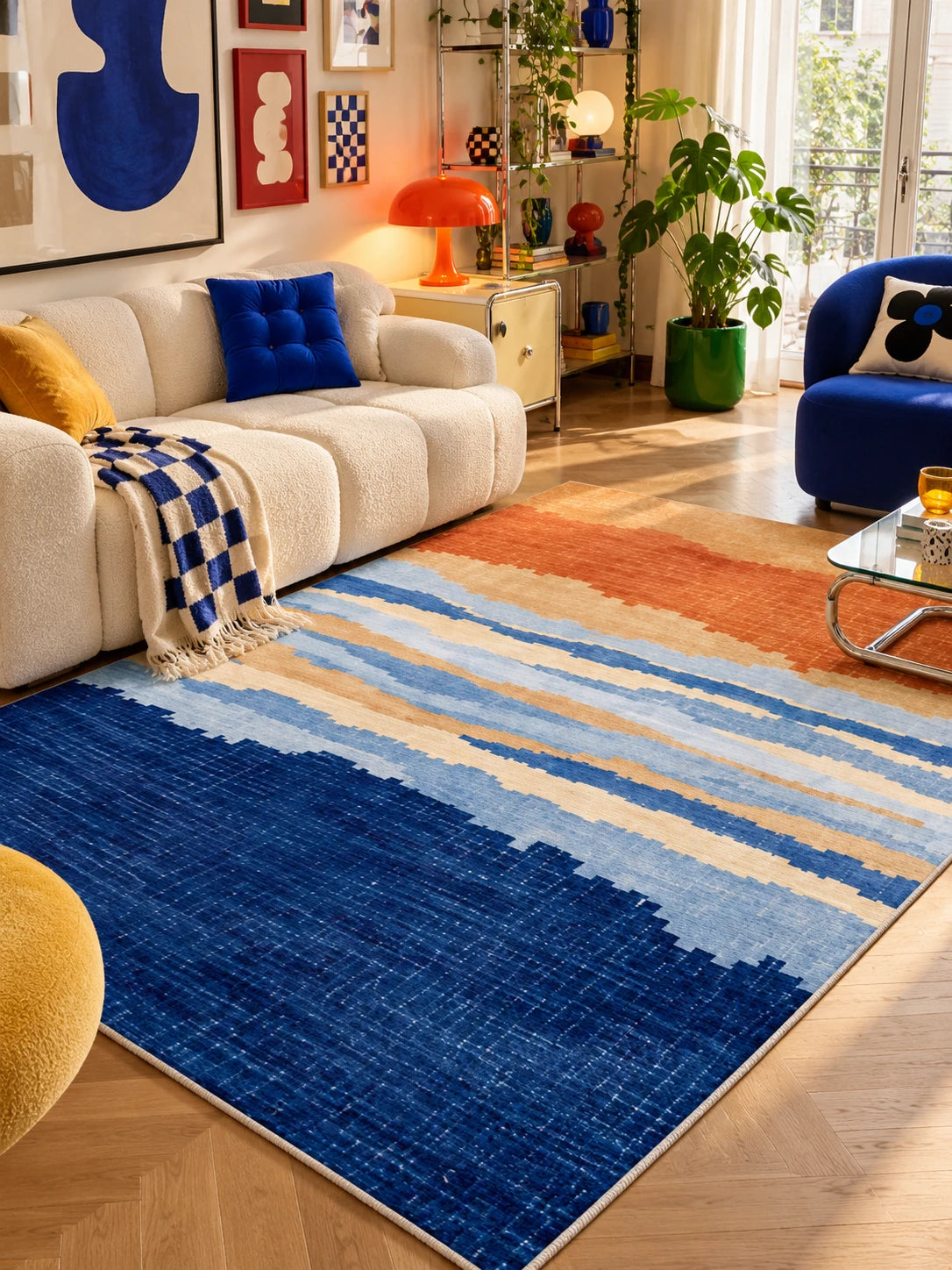 Cobalt-to-orange gradient rug fronting a cream sofa with blue checkerboard throw