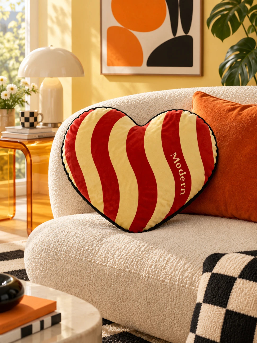 Red and cream wavy heart pillow on a cream boucle sofa against a yellow wall