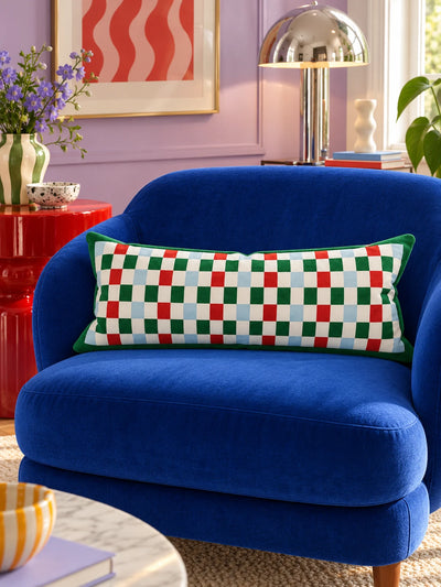 Red and green checkerboard lumbar pillow on a cobalt velvet loveseat in a lilac room