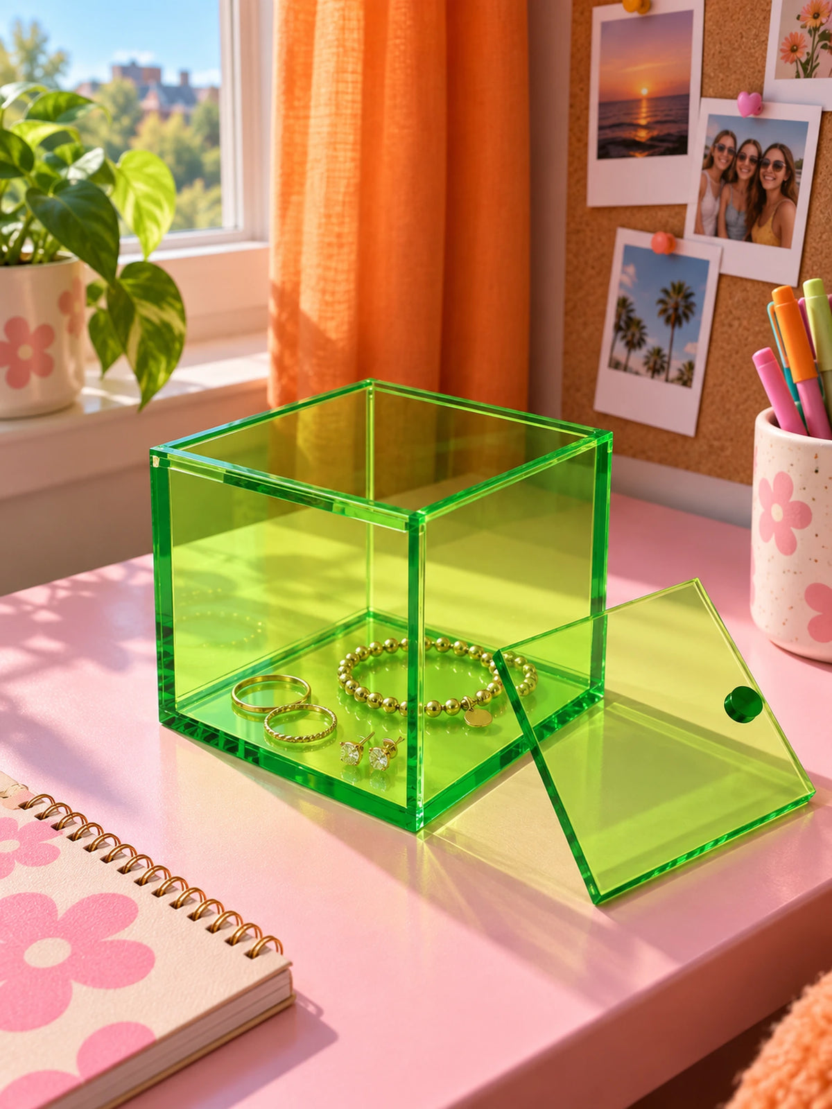 green acrylic storage box with gold jewelry inside on a pink vanity desk