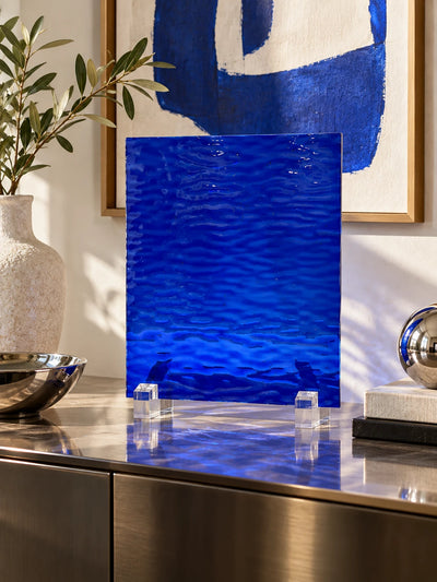 cobalt rippled glass sheet on a steel sideboard with an olive branch vase