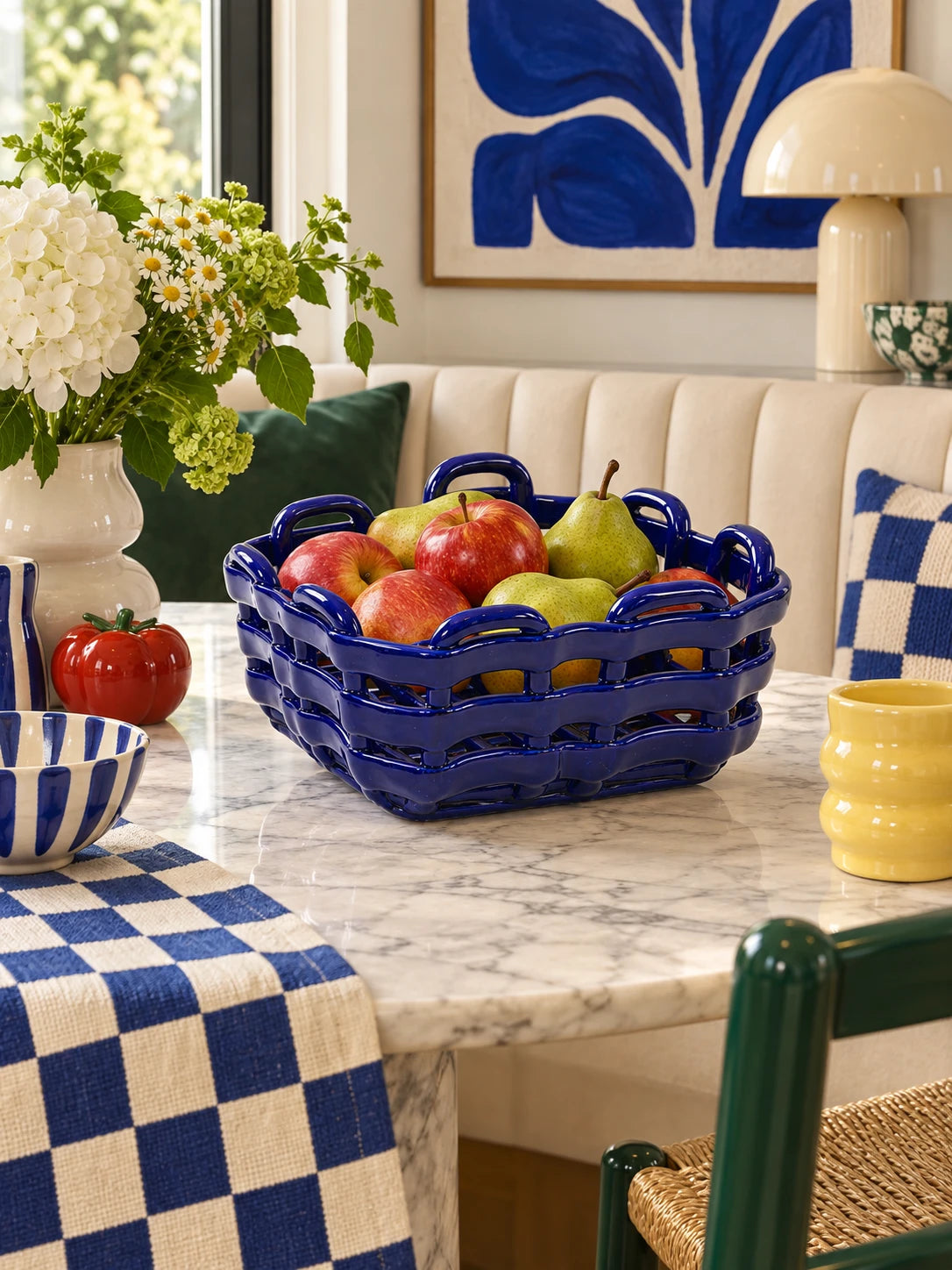 Woven ultramarine basket filled with apples and pears on a marble dining table