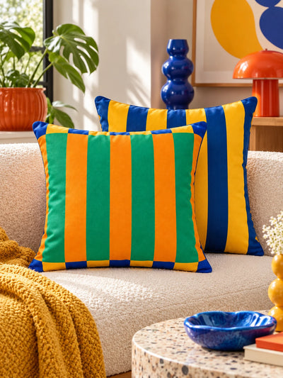 Teal and orange cabana pillow with navy and yellow pillow on a sofa with mustard throw