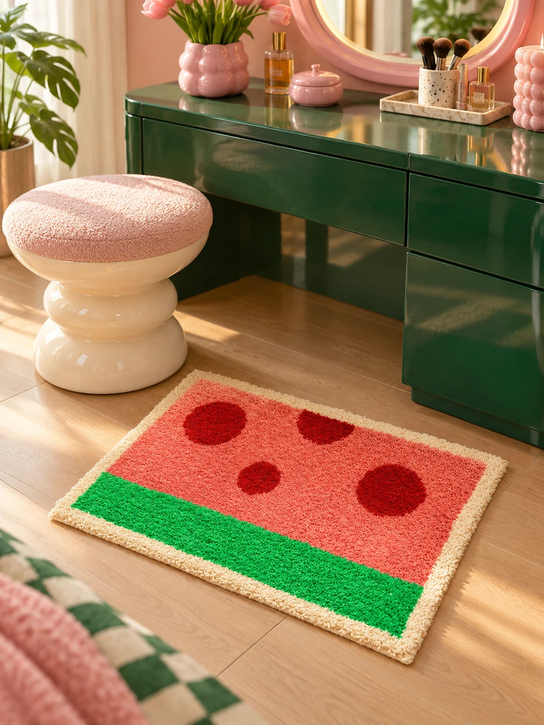 
watermelon flocked mat beside a green vanity desk with a pink boucle stool