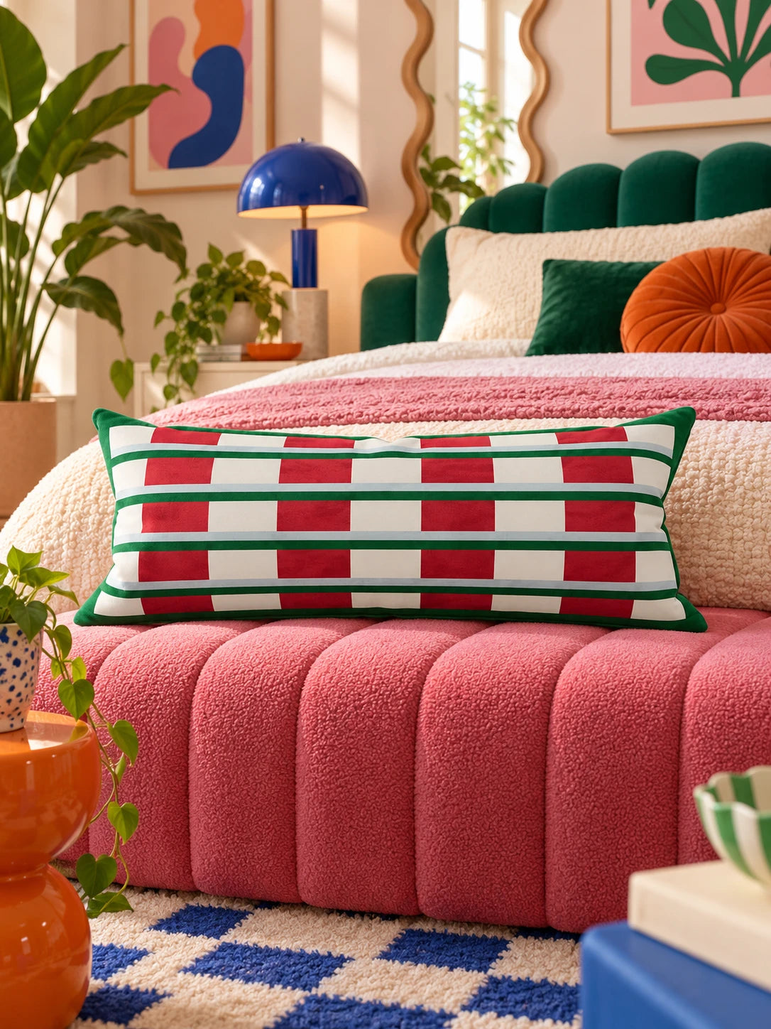 Red and green striped lumbar pillow on a pink channel bench at the foot of a green velvet bed