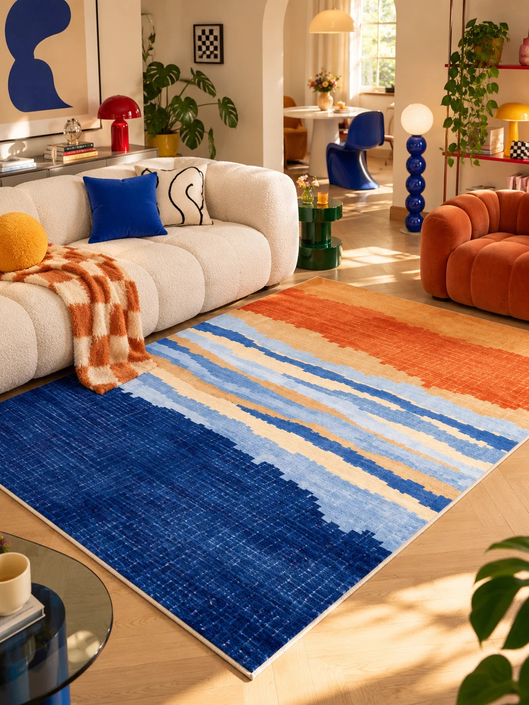 Blue gradient rug beside an orange velvet armchair, rust checkered throw on the sofa