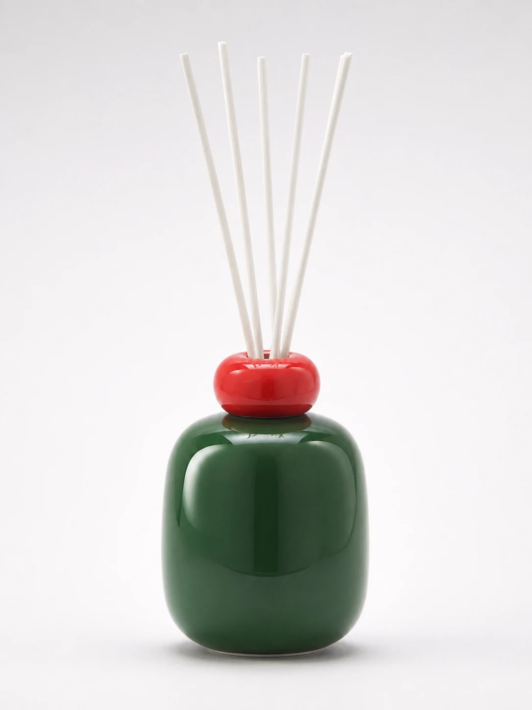 forest green glazed ceramic reed diffuser bottle with a red ring cap and five white reeds